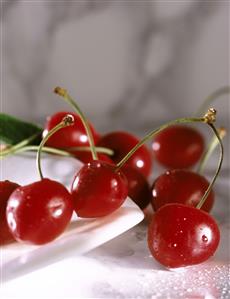 Varias cerezas junto a un plato. 