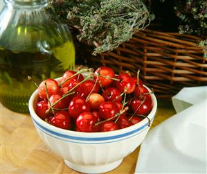 Bol con cerezas. Detras, cesta con romero y espliego.