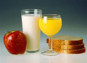 Vaso de leche, zumo de naranja, manzana y pan de molde integral.