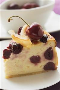 Tarta de queso con cerezas. Receta disponible TR. Piece of cheesecake with cherries and coconut shavings