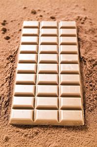 A bar of milk chocolate on cocoa powder