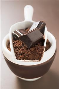 Pieces of chocolate and cocoa powder in scoop and bowl