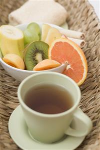 Cup of tea, fresh fruit and towel in basket