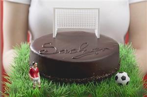 Woman holding Sacher torte with football figure & football