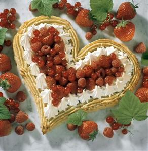 Heart-shaped cake with red berries and cream border