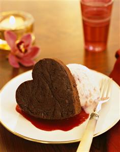 Small heart-shaped chocolate cake with ice cream & fruit sauce