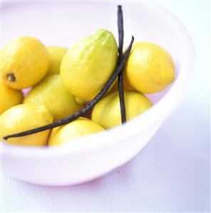 Lemons with vanilla pods in a white dish