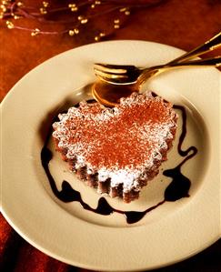 Heart-shaped chocolate cake with chocolate sauce on plate