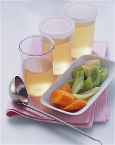 Vegetable broth in jars and a bowl of soup vegetables