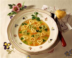 Heart soup with vegetable on plate, heart-shaped roll