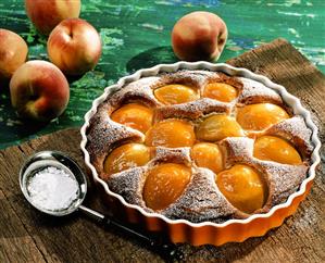 Peach tart with icing sugar in the baking dish