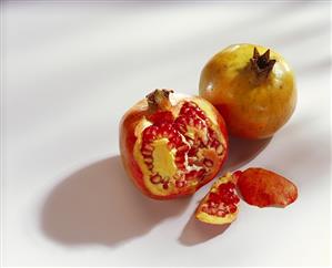 Pomegranates, one with a piece cut off