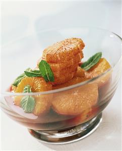Slices of blood orange in sauce with mint leaves