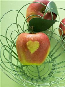 Red apples with heart in and beside wire basket