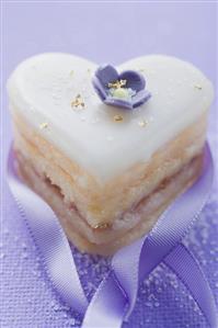 Small heart-shaped cake with sugar flower, gold and ribbon