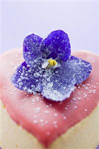 Small heart-shaped cake with pink icing and violet