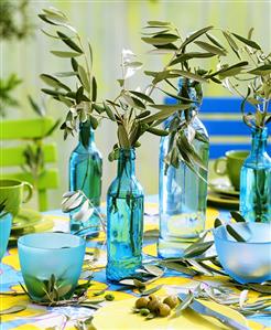 Olive branches in bottles as table decoration