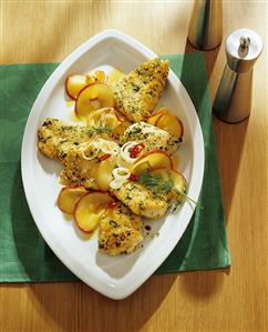 Breaded fish pieces with apple slices, onions and chili