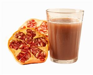 Glass of pomegranate juice and halved pomegranate