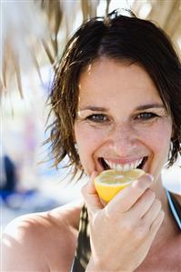 Woman biting into a lemon