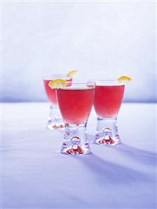 Three pomegranate drinks with pieces of lemon