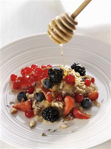 Trickling honey over muesli with berries