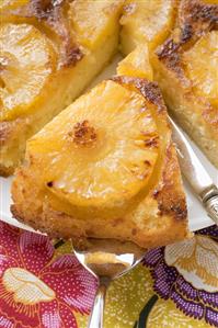 Pineapple upside-down cake, a piece on server (close-up)