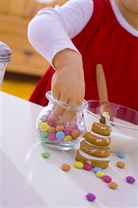 Decorating biscuit Christmas tree with chocolate beans