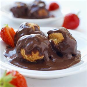 Profiteroles with chocolate sauce and strawberries