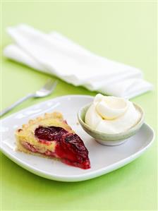 Piece of plum tart with cream