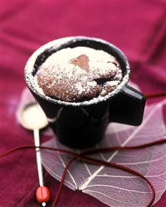 Chocolate soufflé dusted with icing sugar in a cup