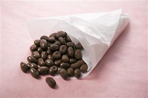 Chocolate Covered Raisins Spilling From a Paper Cone