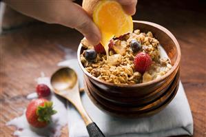 Squeezing wedge of orange over muesli