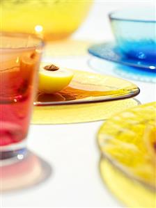 Half a yellow plum and coloured glass tableware