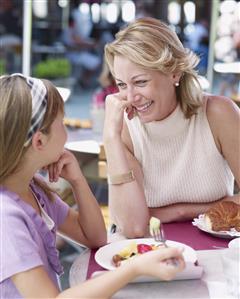 Woman and young girl on outdoor patio eating meal