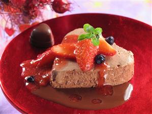 Mousse de chocolate en forma de corazon con salsa de fresones. Receta disponible.
